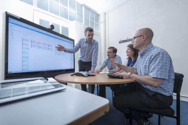 A software engineer presenting work to a small team on an interactive surface