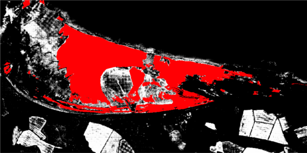 The same black and white aerial image of blue anchor, with a section of the white area (that indicates sand) now shaded in red.