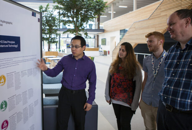 A UKHO staff member presenting the data principles to three other staff members in the UKHO building