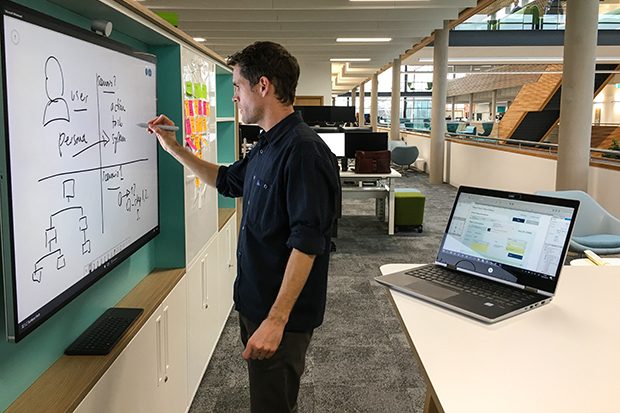 User experience lead reviewing user design system on whiteboard at the UK Hydrographic Office