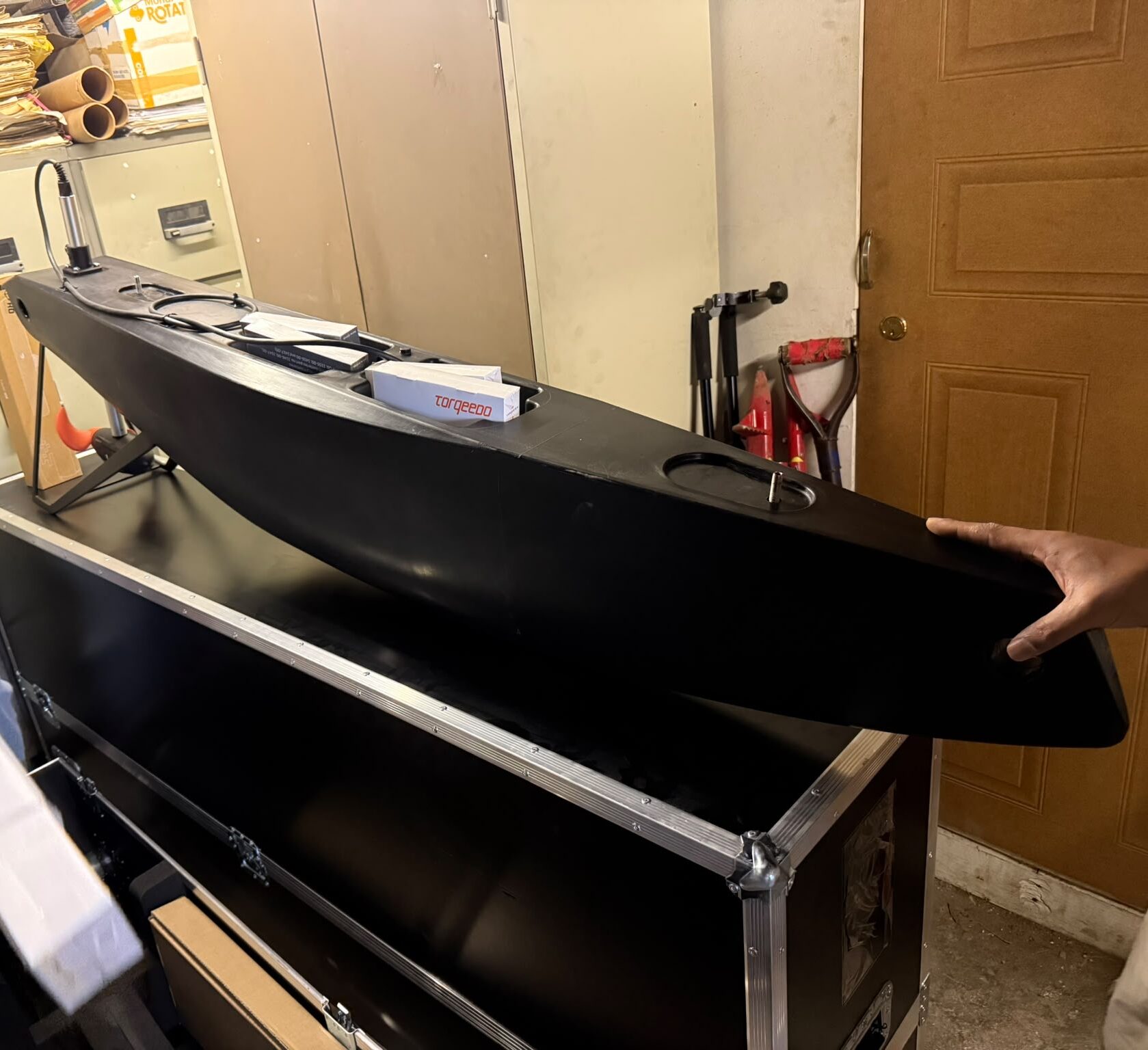 Two people unpack a large piece of surveying equipment from a wooden transport box as part of an equipment loan.