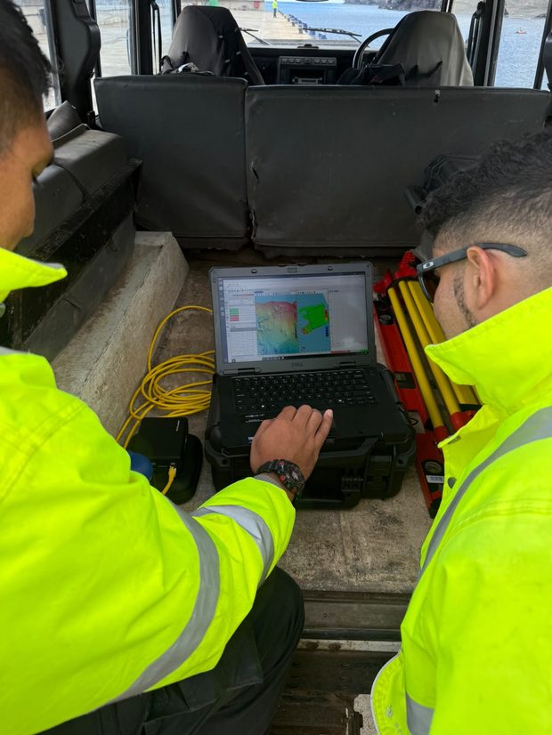 Two team members examine survey data collected during a survey operation aboard a vessel.