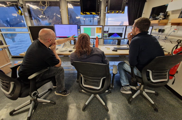 Three scientists sat in front of computer screens analysing data from wreck investigations.
